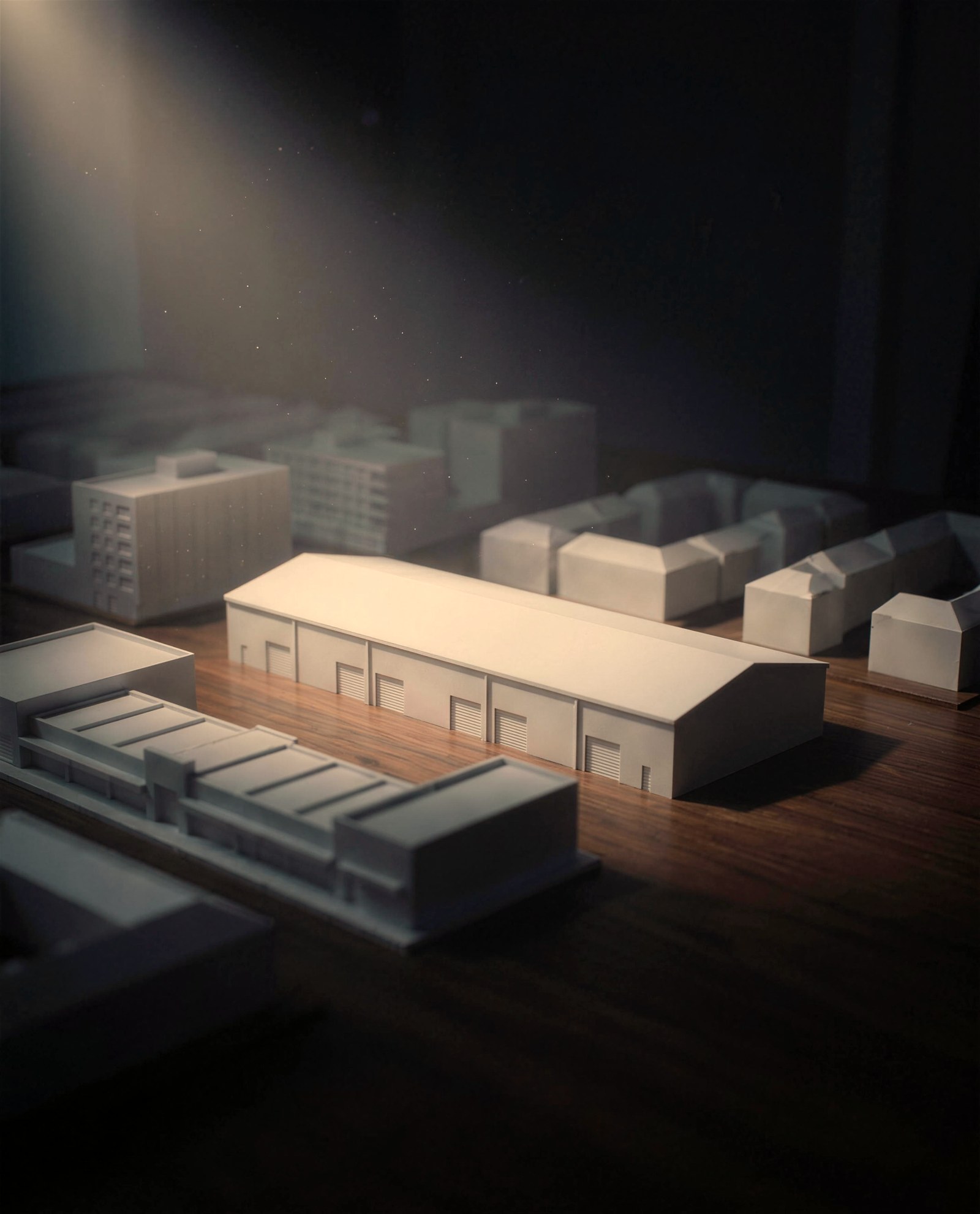 A white architectural model of a warehouse with loading docks under a single spotlight