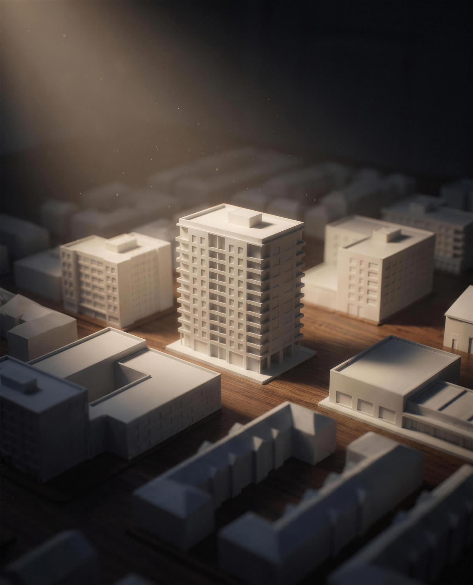 A white architectural model of a mid-rise apartment building lit by a single warm spotlight